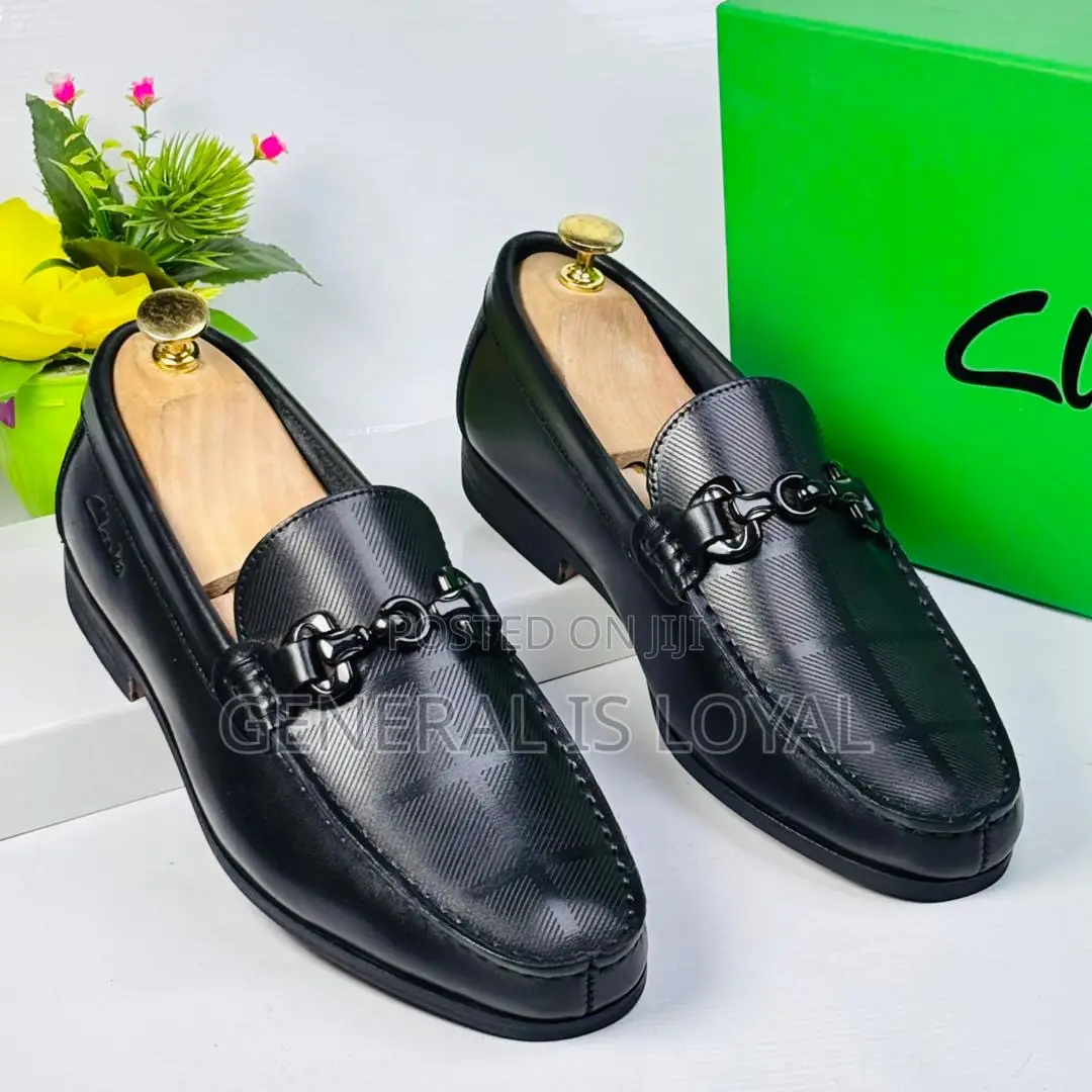 Black Clarks Loafers With A Metal Buckle And Patterned Leather
