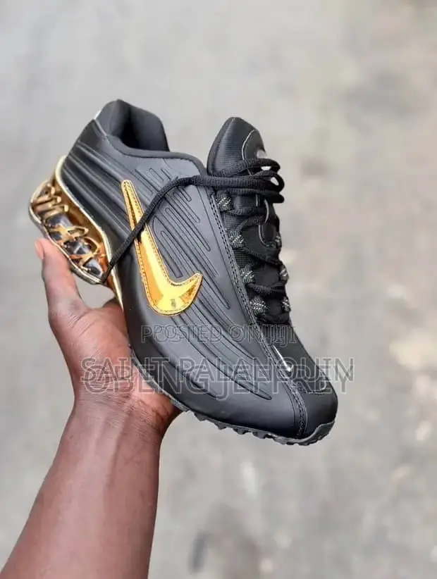 A Black Nike Sneaker With a Glossy Upper and a Metallic Gold Swoosh