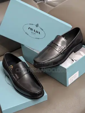 A Pair of Black Leather Penny Loafers Featuring a Keeper Strap
